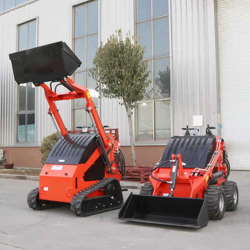 Two red compact track loaders parked on a street with a building in the background.